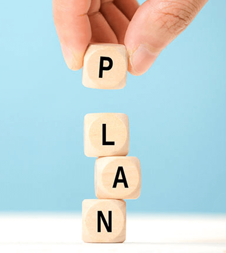 Hand stacking tiny blocks that spell out Plan