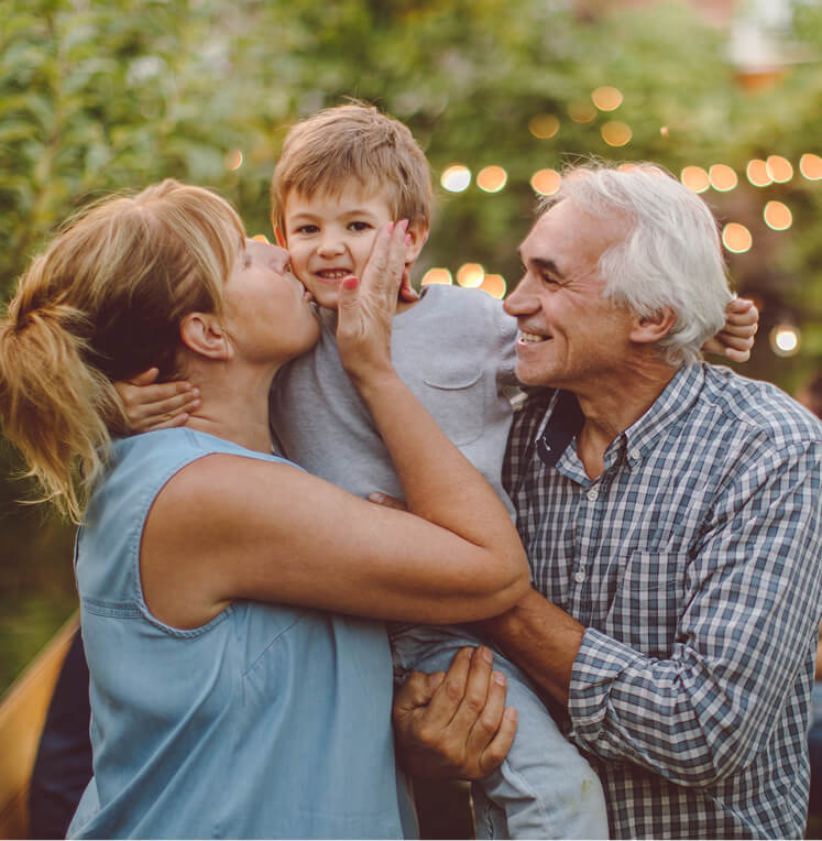 Grandparents hugging their grandchild